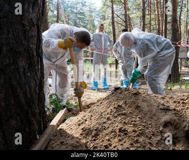 19 septembre 2022, Izyum, Ukraine: Les enquêteurs portant des engins de protection sont vus exhumanter des corps avec des pelles. Un site de sépulture de masse a été trouvé dans la périphérie de la ville ukrainienne orientale, Izyum, région de Kharkiv, qui a été libérée de l'occupation russe il y a deux semaines. Au moins 445 nouvelles tombes ont été trouvées sur le site d'un cimetière existant alors que beaucoup n'ont que des numéros écrits sur la croix en bois. Tous les corps seront exhumés et envoyés pour examen médico-légal mais il a été dit lors des premières enquêtes que certains organes ont montré des signes de torture. (Credit image: © Ashley Chan/SOPA Images via ZUMA Banque D'Images