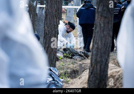 19 septembre 2022, Izyum, Ukraine: (NOTE DE LA RÉDACTION: Image dépeint la mort).un investigateur portant des équipements de protection est vu examiner un corps exhumé. Un site de sépulture de masse a été trouvé dans la périphérie de la ville ukrainienne orientale, Izyum, région de Kharkiv, qui a été libérée de l'occupation russe il y a deux semaines. Au moins 445 nouvelles tombes ont été trouvées sur le site d'un cimetière existant alors que beaucoup n'ont que des numéros écrits sur la croix en bois. Tous les corps seront exhumés et envoyés pour examen médico-légal mais il a été dit lors des premières enquêtes que certains organes ont montré des signes de torture. (Image crédit : © Banque D'Images