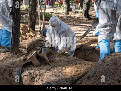 19 septembre 2022, Izyum, Ukraine: (NOTE DE LA RÉDACTION: Image dépeint la mort).un investigateur portant des équipements de protection est vu examiner un corps exhumé. Un site de sépulture de masse a été trouvé dans la périphérie de la ville ukrainienne orientale, Izyum, région de Kharkiv, qui a été libérée de l'occupation russe il y a deux semaines. Au moins 445 nouvelles tombes ont été trouvées sur le site d'un cimetière existant alors que beaucoup n'ont que des numéros écrits sur la croix en bois. Tous les corps seront exhumés et envoyés pour examen médico-légal mais il a été dit lors des premières enquêtes que certains organes ont montré des signes de torture. (Image crédit : © Banque D'Images