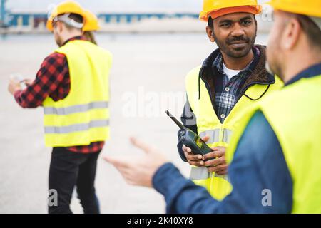 Travailleurs contrôlant les conteneurs d'expédition dans le port industriel extérieur - Focus sur les mains d'homme indien tenant le walkie-talkie Banque D'Images