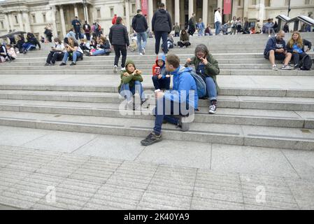 Londres, Angleterre, Royaume-Uni. Jeune famille assis sur les marches de Trafalgar Square menant à la Galerie nationale Banque D'Images