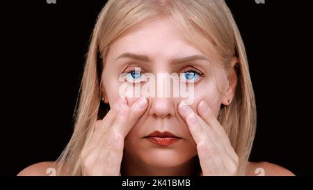 Deuxième menton, obésité. Portrait d'une femme de 30 ans tirant la peau vers l'arrière sur ses joues regarde la caméra avec un regard frustré. Problèmes de vieillissement Banque D'Images