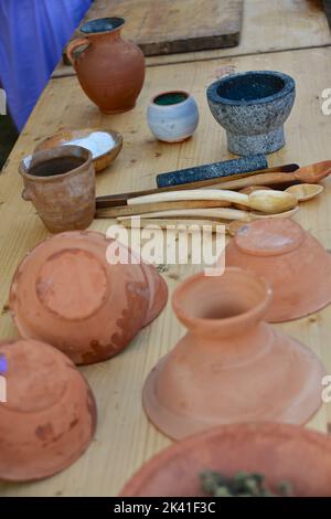 Assiettes, pots et objets faits d'argile sur la table avec des cuillères et du mortier de granit Banque D'Images