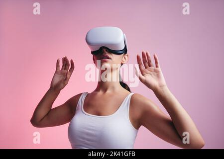 En regardant autour du métaverse. Jeune femme explorant la technologie immersive dans un studio. Jeune femme entrant dans un jeu de 3D tout en portant une réalité virtuelle h Banque D'Images