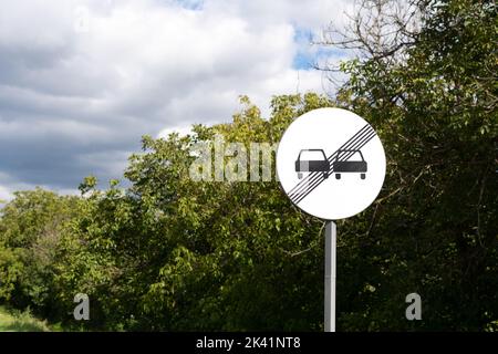 Panneau de signalisation : fin de la zone d'interdiction de dépassement. Road Sign annulation de la limitation précédente. Panneau rond avec deux voitures noires et des lignes noires à l'arrière Banque D'Images