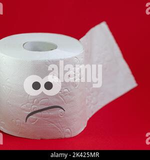 Papier toilette avec face en colère contre fond rouge Banque D'Images