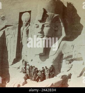 Groupe de touristes en Lap of Colossus, Egypte 1900s Banque D'Images