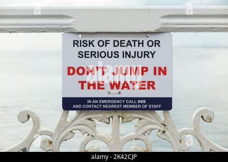 Un panneau d'avertissement de sécurité indique aux gens de ne pas sauter / pas plonger dans l'eau de mer depuis Brighton Palace Pier. Madeira Drive, Brighton, East Sussex. (131) Banque D'Images