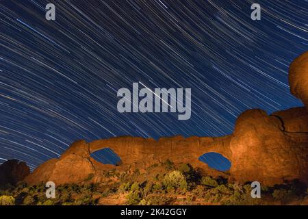 Des pistes étoiles au-dessus des fenêtres nord et sud la nuit dans la section Windows du parc national d'Arches, Moab, Utah. Banque D'Images