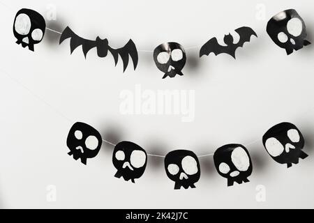 Chauves-souris et crânes noirs sur fond blanc, endroit pour écrire un message d'accueil, artisanat en papier pour Halloween. Banque D'Images