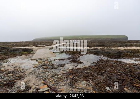 Touristes marchant le long de la voie de béton à l'île de Brough de Birsay, le continent d'Orkney, Écosse, Royaume-Uni Banque D'Images