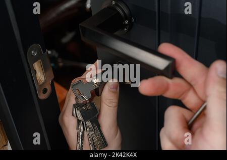 Le maître installe le noyau de la serrure de porte, le travail d'assemblage avec la porte, le noyau avec les clés. Banque D'Images