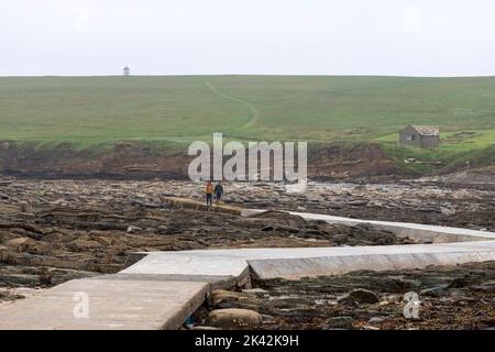 Touristes marchant le long de la voie de béton à l'île de Brough de Birsay, le continent d'Orkney, Écosse, Royaume-Uni Banque D'Images