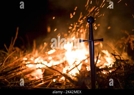 Gros plan de l'épée des Templiers dans le sol par le feu Banque D'Images