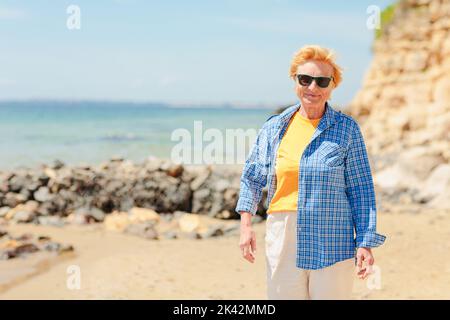 Femme âgée marchant sur la plage près de la mer Banque D'Images