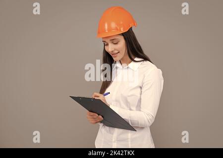 Femme d'affaires avec presse-papiers, portrait sur gris. Portrait d'une femme employée dans un casque de casque. Banque D'Images