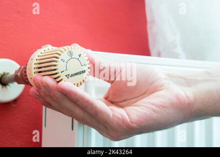 Maintenir le thermostat sur le radiateur à la main pour régler la température. Crise énergétique en Europe. Électricité coûteuse et manque de gaz. Les prix augmentent. Banque D'Images