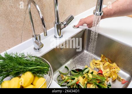 Mise en marche d'un broyeur dans une cuisine moderne pour éliminer les déchets alimentaires Banque D'Images