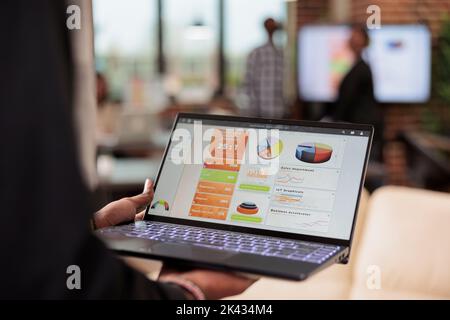 Homme d'affaires analysant des graphiques et des graphiques sur ordinateur portable, en utilisant le navigateur de site Web. Vérification des informations de démarrage sur le diagramme pour créer une présentation sur ordinateur dans la salle de réunion, à l'aide des données de recherche en ligne. Gros plan. Banque D'Images