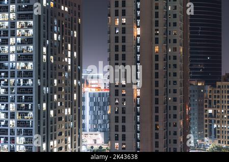 Façades de plusieurs grandes maisons résidentielles, gratte-ciel la nuit avec fenêtres illuminées et ciel pourpre en arrière-plan; altitude de la maison de puits de ciel Banque D'Images