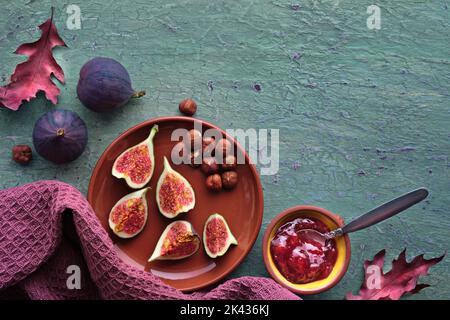 Arrière-plan automatique avec fruits frais coupés en deux sur une plaque en céramique de terre cuite. Serviette magenta et feuilles d'automne rouges sur turquoise, vert menthe texturé Banque D'Images