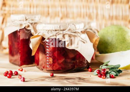 Pots de confiture de mûres et de poires maison avec papier artisanal sur les couvercles sur la surface en bois à côté des mûres et poires fraîches. Banque D'Images