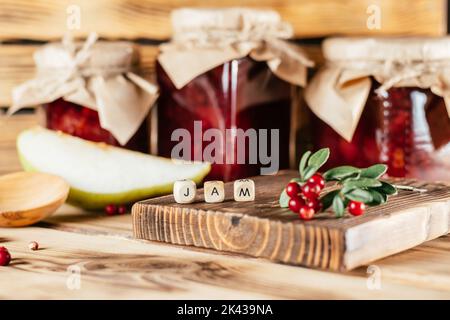 Pots de confiture de mûres et de poires maison avec papier artisanal sur les couvercles sur la surface en bois à côté des mûres et poires fraîches. Banque D'Images