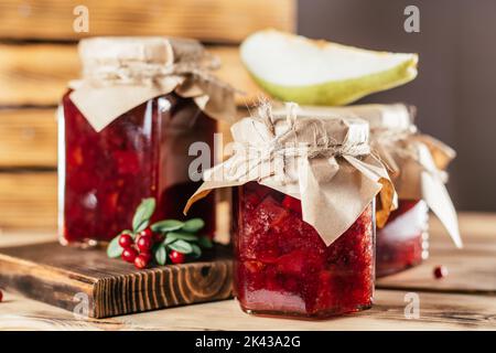 Pots de confiture de mûres et de poires maison avec papier artisanal sur les couvercles sur la surface en bois à côté des mûres et poires fraîches. Banque D'Images