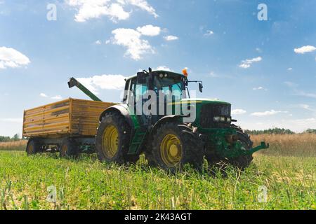 Récolte estivale. Travailler dans un champ. Concept de campagne. Photo pleine longueur d'un tracteur géant professionnel et d'une remorque agricole jaune. Photo de haute qualité Banque D'Images