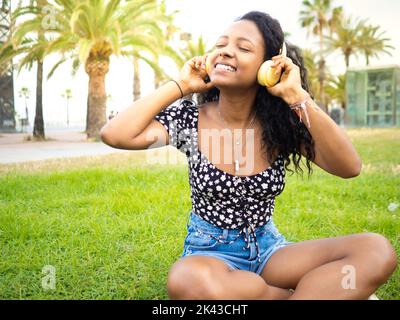 Jeune afro-américaine écoutant de la musique en souriant avec un casque Banque D'Images