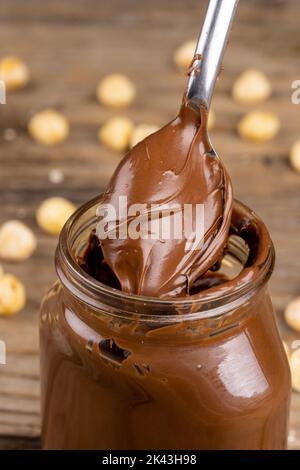 Image verticale de la cuillère avec de la crème au chocolat et des noix sur une surface en bois Banque D'Images