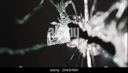 Gros plan d'un panneau de verre cassé et fissuré avec trou, sur fond noir avec espace de copie Banque D'Images