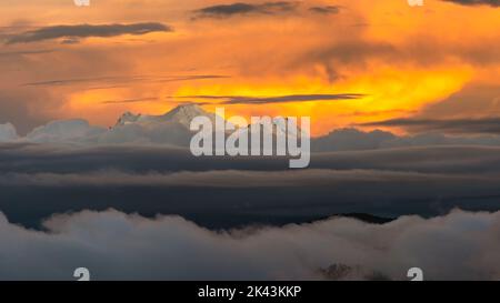 Vue panoramique sur le volcan Antisana illuminé par une magnifique lumière de coucher de soleil. Cette image est prise de la partie ouest de Quito et d'une banque de nuages et de mi Banque D'Images