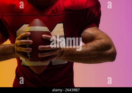 Section médiane d'un joueur américain de football américain de race blanche avec éclairage violet et jaune néon Banque D'Images