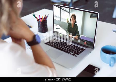 Composition d'une femme d'affaires biraciale ayant un appel vidéo avec un collègue. Image générée numériquement par le concept global de gestion et de traitement des données. Banque D'Images