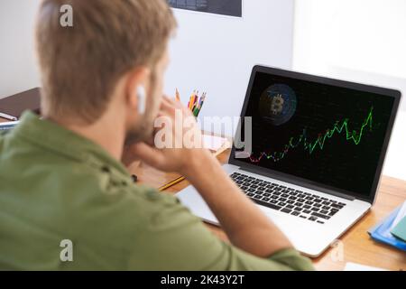 Homme d'affaires caucasien assis à un bureau à l'aide d'un ordinateur portable avec graphique et données statistiques à l'écran. Communication d'entreprise et technologie d'interface numérique Banque D'Images