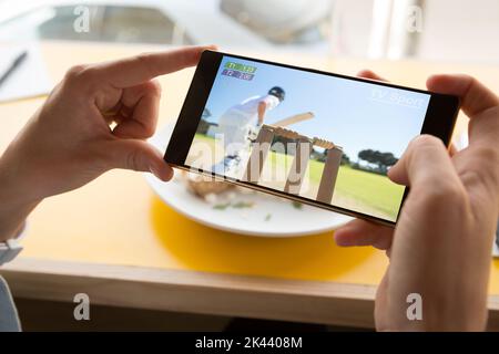 Mains de l'homme caucasien au restaurant regardant un smartphone avec match de baseball à l'écran. Sport, compétition, divertissement et technologie concept digi Banque D'Images