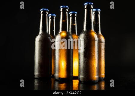 Illustration de six bouteilles de bière avec bouchons à couronne bleus, avec espace de copie sur fond noir Banque D'Images