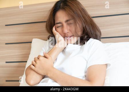 Une adolescente qui appuie sur sa joue ecchymoisée avec une expression douloureuse comme si elle avait un mal de dents terrible. Banque D'Images