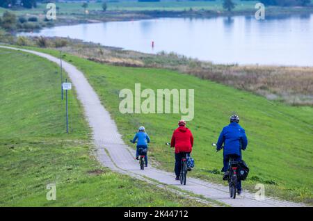 PRODUCTION - 27 septembre 2022, Mecklembourg-Poméranie occidentale, Dömitz : les cyclistes sont sur la digue le long de l'Elbe. Une semaine de la biosphère célèbre le 25th anniversaire de la Réserve de biosphère de l'UNESCO, le paysage de l'Elbe. Le paysage de la rivière Elbe couvre 278 660 hectares. Le 30 septembre 2022, les cinq États riverains du gouvernement fédéral célébreront cet anniversaire. Photo: Jens Büttner/dpa Banque D'Images