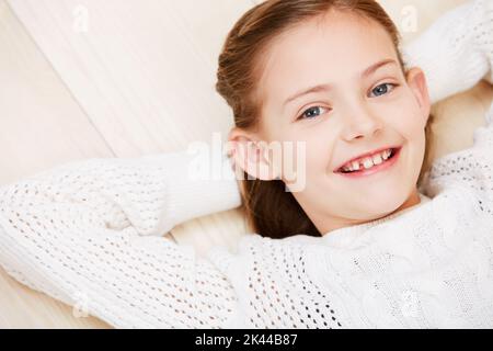 La simplicité. Portrait court d'une petite fille mignonne souriant tout en étant couché et en se relaxant. Banque D'Images