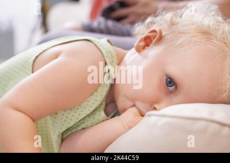 Elle est tout simplement adorable. Un jeune enfant mignon aux cheveux bouclés blonds en regardant avec timidement l'appareil photo. Banque D'Images