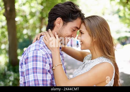 Romance de parc. Un jeune couple heureux debout bras dans bras ensemble dans un parc. Banque D'Images