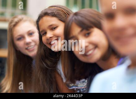 Amitié et sourires. Portrait d'une jeune fille debout parmi ses amis de l'école. Banque D'Images