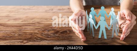 Employee Hands Protecting Cutout Paper People. Equal Human Concept Stock Photo