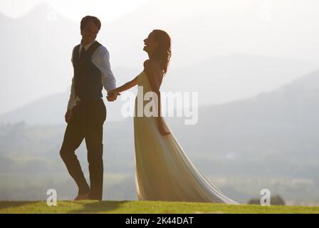 Amour et rire. Une belle mariée et marié marchant main dans la main. Banque D'Images