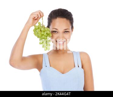 Voulez-vous en avoir. Jeune femme souriant tout en tenant une bande de raisin - isolé sur blanc. Banque D'Images