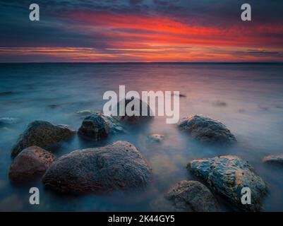 Coucher de soleil d'automne côtier coloré avec rochers humides et surf en mer à Botnerbaugen à Larkollen, sur la côte est de l'Oslofjord, Østfold fylke, Norvège. Banque D'Images