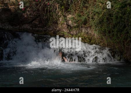 Une femme israélienne se baigne dans un bassin naturel d'eau de source du ruisseau Amal qui traverse le parc national de Gan Hashlosha également connu sous son nom arabe Sakhne en Israël Banque D'Images