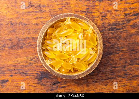 Capsules d'huile de poisson dans un bol. Pilules jaunes omega 3 sur la table en bois. Vue de dessus. Banque D'Images